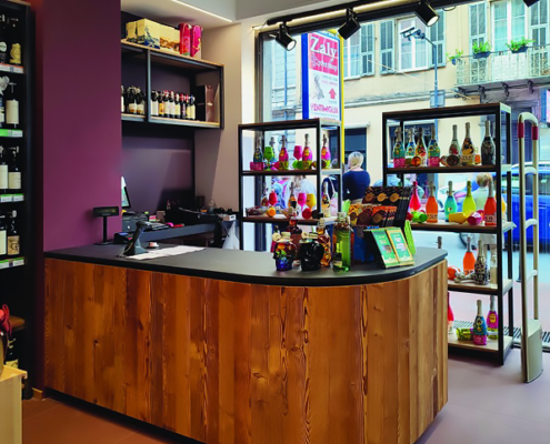 Vista frontale di un bancone/cassa realizzato in legno e con una copertura nera all'interno di una vineria.